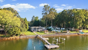 A lakeside property with a dock, houses, and a well-maintained lawn.