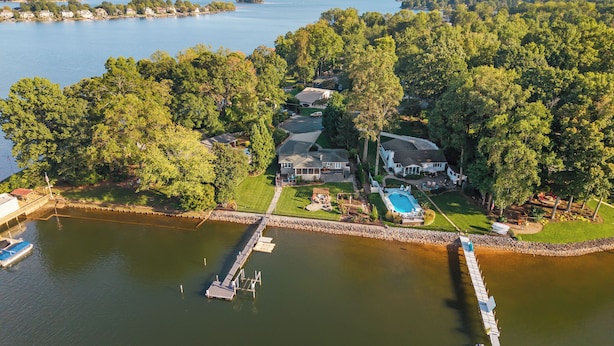 A lakeside property with a dock, a swimming pool, and a well-maintained lawn.