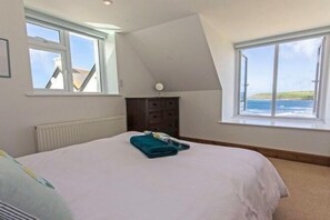 A bedroom with a bed, two windows, a radiator, and a dresser.