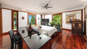 Habitació d'hotel amb un llit, escriptori amb cadira, televisió i ventilador de sostre.