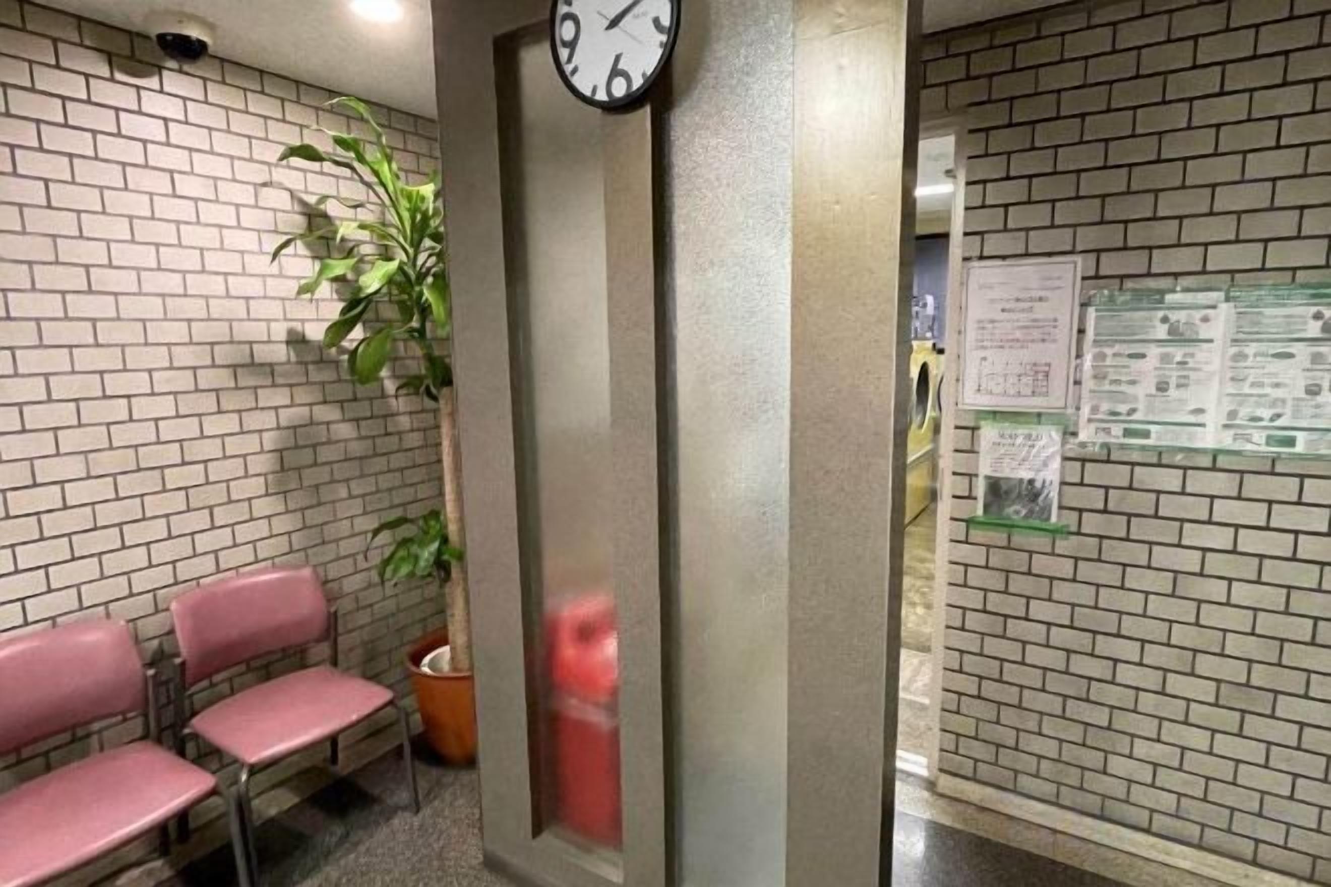 Une salle d’attente avec une horloge, des chaises et des affiches informatives sur les murs.