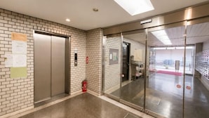 An elevator, a fire extinguisher, and a glass door leading to a room with a red carpet. - Lions Mansion Dogenzaka SHIBUYA (Tokyo)