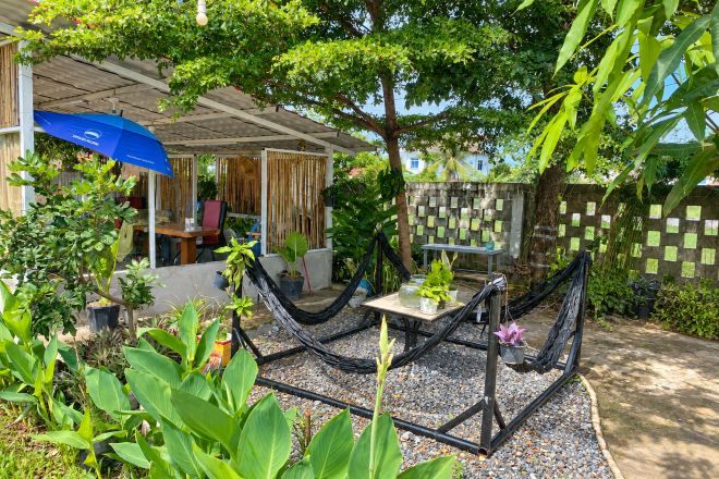 Un jardín con una hamaca, una mesa y un paraguas azul.