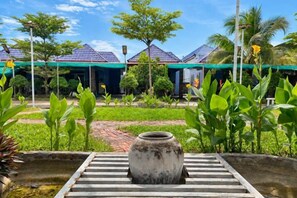 A courtyard with a large pot, a pathway, and a building with a tiled roof.