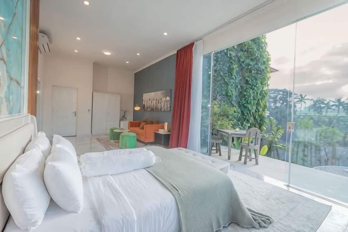 A modern bedroom with a large bed, a balcony with a view, and a separate living area.