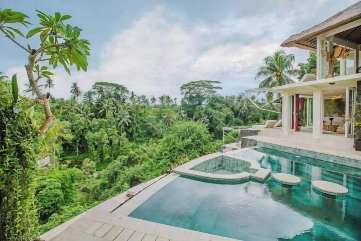 A pool with a view of lush greenery and a building with large windows.
