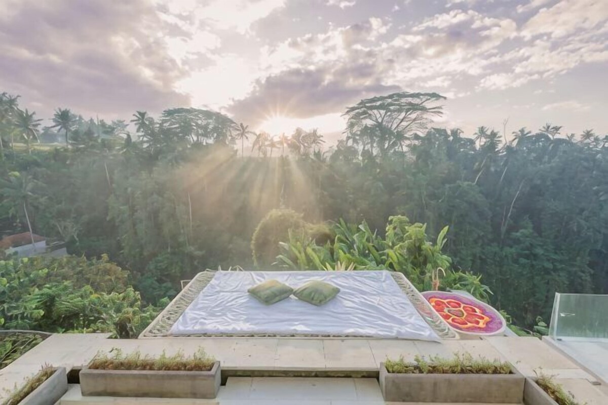 A rooftop terrace with a bed, pillows, and a decorative mat.