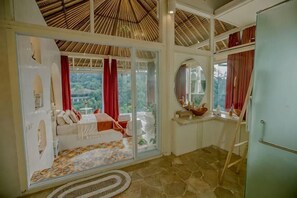 A bedroom with a bed, a window, a mirror, and a wardrobe.