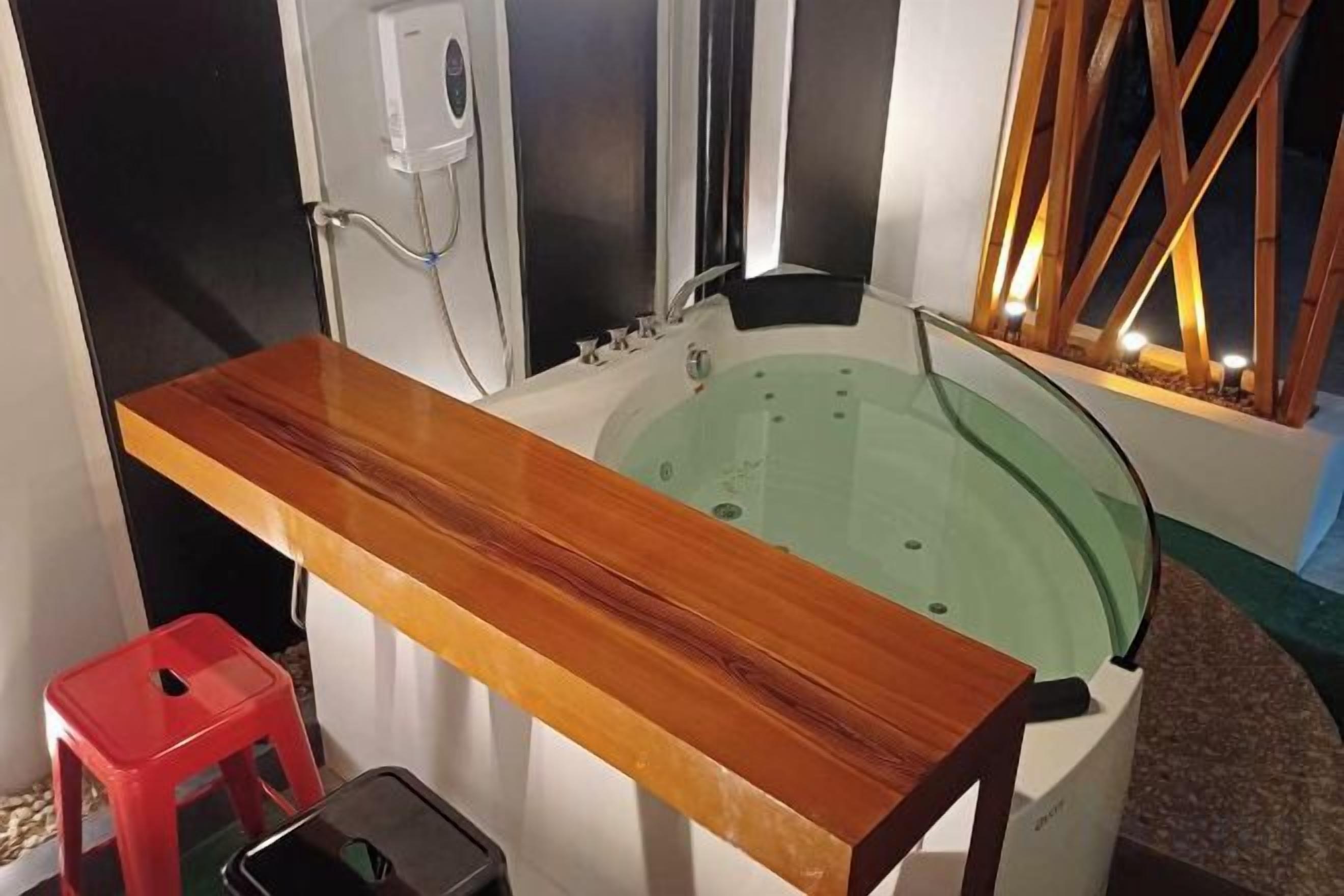 A bathroom with a wooden vanity, a bathtub, and a red stool.