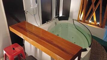 A bathroom with a wooden vanity, a bathtub, and a red stool.
