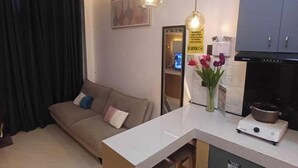 En kompakt opholdsstue med et tekøkken, en sofa, et spisebord og en hængende lampe.