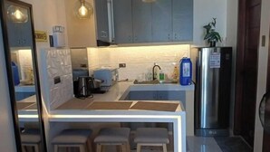 Et moderne køkken med en central ø, barstole, et stålskab og en vask.
