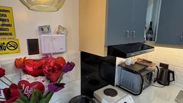 A kitchen with a microwave, coffee maker, and a small appliance on the counter. There are red and purple tulips with a heart-shaped balloon on the counter.