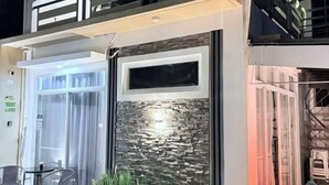 En moderne bygning med en glasdør, en stenvæg og en balkon med gelændere.