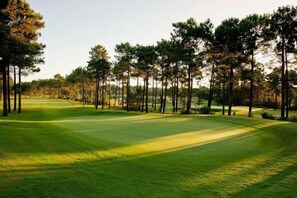 A golf course with a well-maintained fairway, trees lining the edges, and a clear sky. - BelArt Golf Villa (Charneca de Caparica e Sobreda)