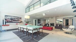 Ein modernes Interieur mit Essbereich, einem roten Sofa und einer Treppe.