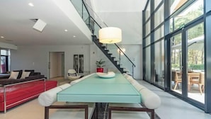 Ein moderner Essbereich mit einem langen Tisch, weißen Stühlen und einem roten Sofa.