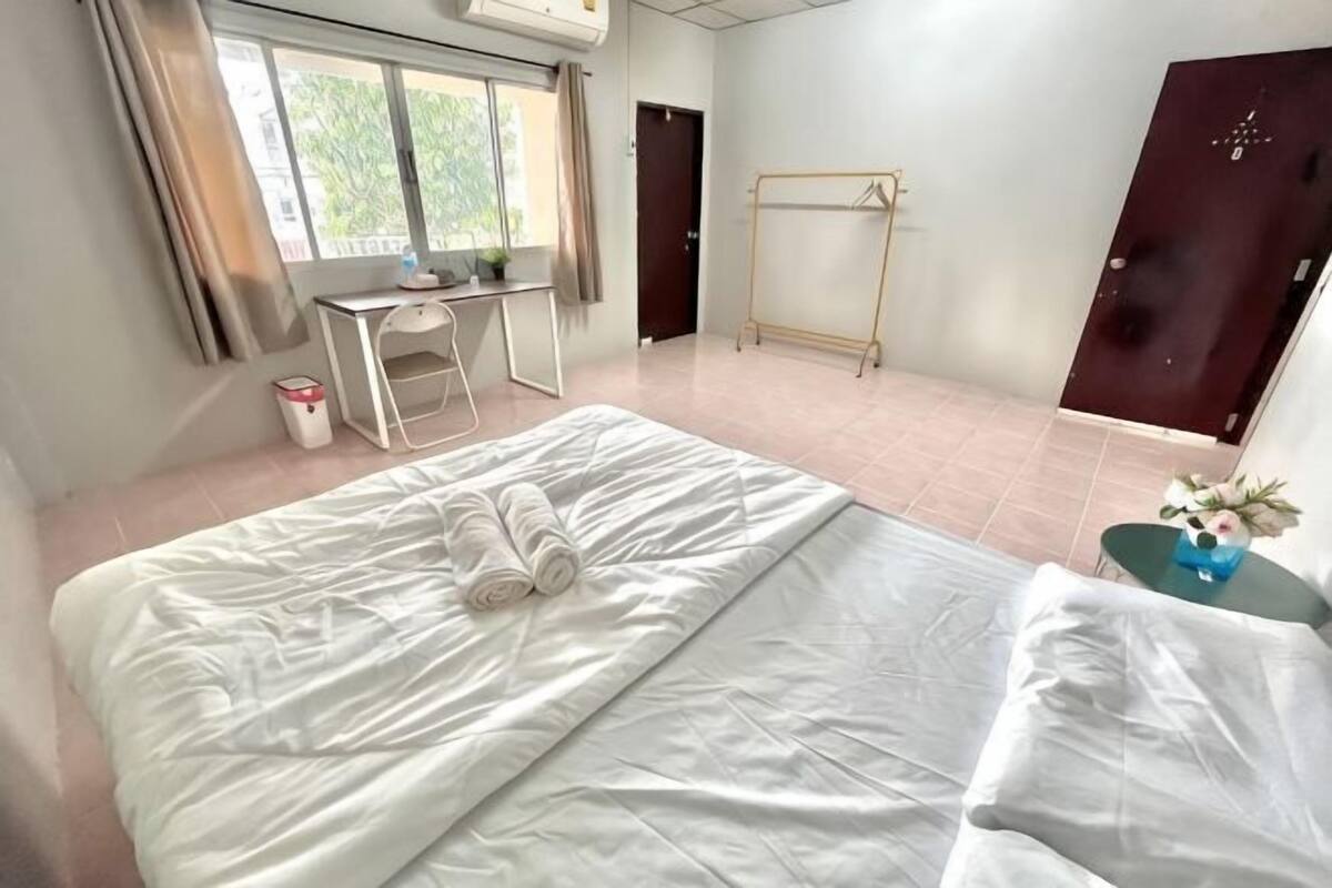 A hotel room with a bed, a desk, a chair, a wardrobe, and a window.