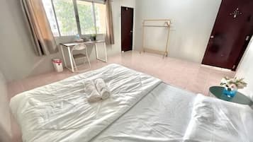 A hotel room with a bed, a desk, a chair, a wardrobe, and a window.