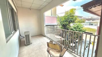 A balcony with a chair, a table, and a potted plant.