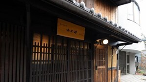 Ein traditionelles japanisches Gebäude mit Holzfassade, einer Schiebetür und einem Schild.