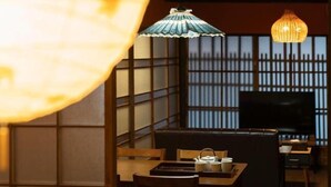 Ein traditioneller japanischer Raum mit Tatami-Böden, einem niedrigen Tisch mit Teeservice und einem Fernseher auf einem Standfuß.