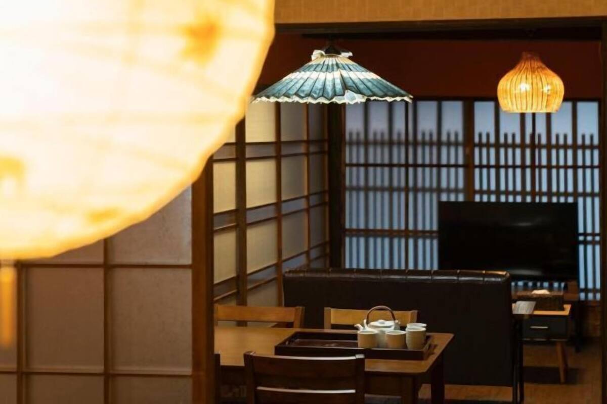 Une pièce de style japonais traditionnel, avec un sol recouvert de tatamis, une petite table basse sur laquelle est disposé un service à thé, et un téléviseur posé sur un meuble.