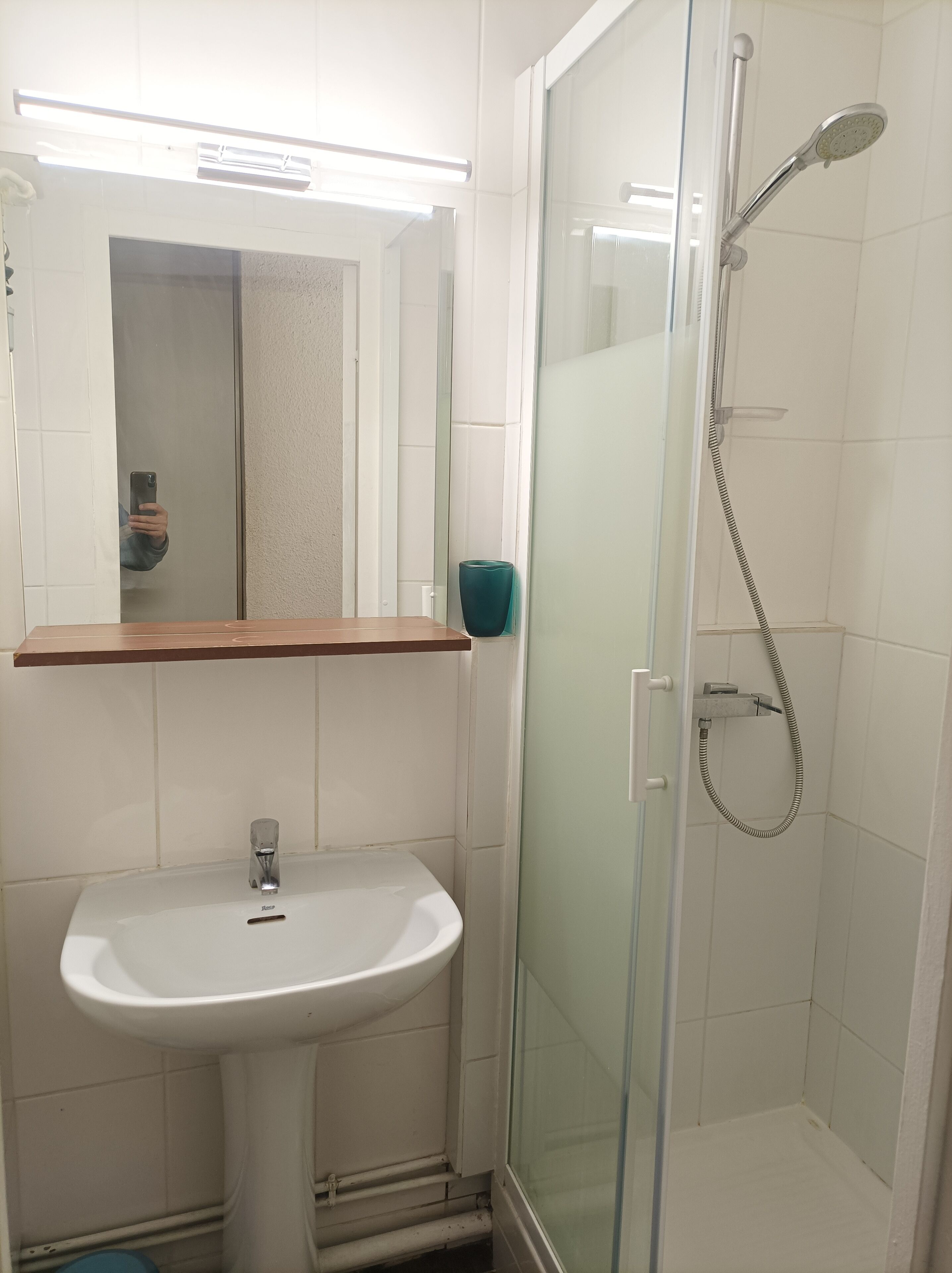 A bathroom with a sink, mirror, and glass-enclosed shower.