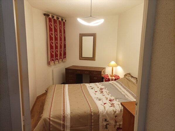 A bedroom with a bed, a dresser, a mirror, and a lamp.