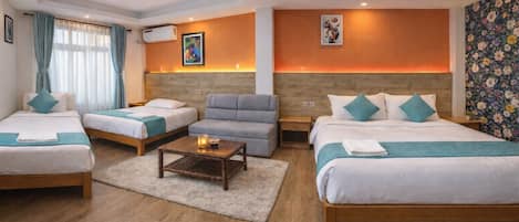 Une chambre d’hôtel avec deux lits, un canapé, une table basse et un papier peint à motifs floraux.