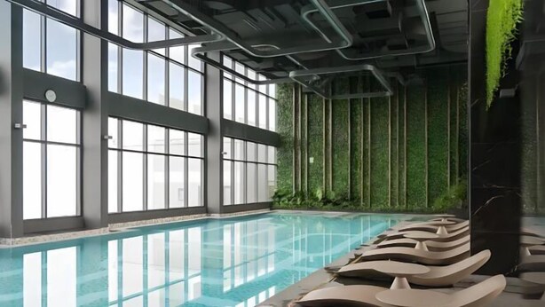 A swimming pool with clear water, surrounded by large windows and indoor plants. - Vinhomes Smart City Apartment Ha Noi - BK Homes (Hanoi)