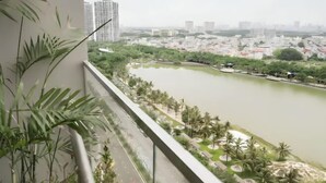 A balcony with a view of a river, greenery, and distant buildings. - Vinhomes Smart City Apartment Ha Noi - BK Homes (Hanoi)