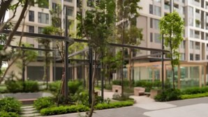 A modern outdoor area with a pathway, greenery, and a glass structure. - Vinhomes Smart City Apartment Ha Noi - BK Homes (Hanoi)