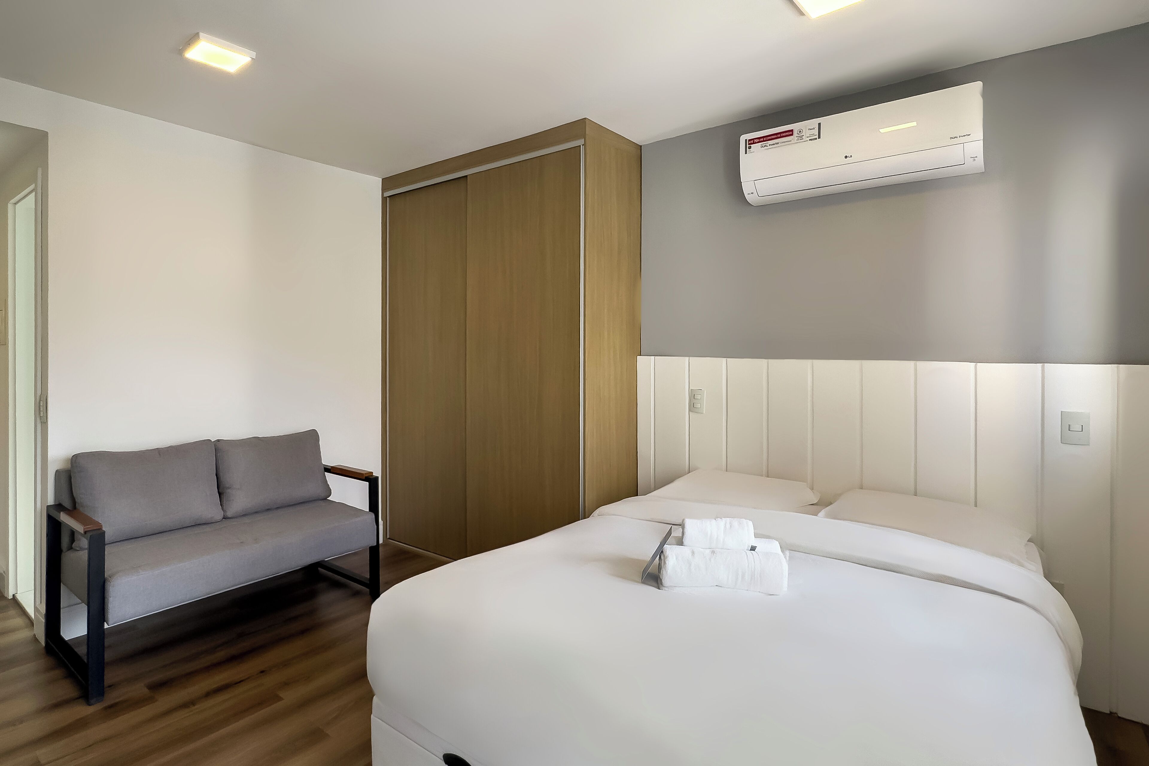 Ein Hotelzimmer mit einem Bett, einer Couch, einem Holzschrank und einer Klimaanlage.