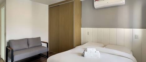 Ein Hotelzimmer mit einem Bett, einer Couch, einem Holzschrank und einer Klimaanlage.
