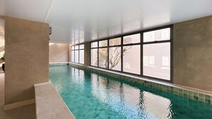 An indoor swimming pool with clear blue water, large windows, and a tiled floor. - Carinas 301 By WeCare (São Paulo)