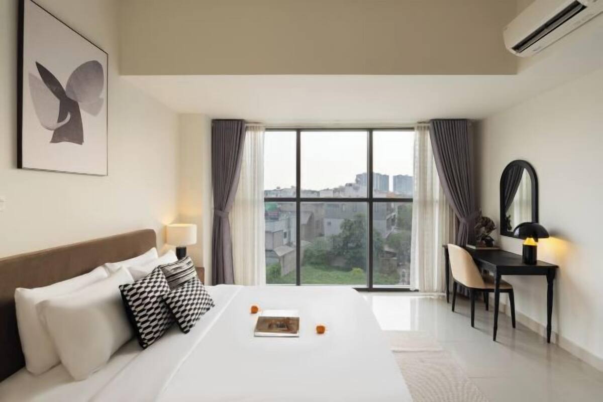 Une chambre d’hôtel équipée d’un lit, d’un bureau, d’une chaise, d’une fenêtre avec des rideaux et d’un appareil de climatisation.