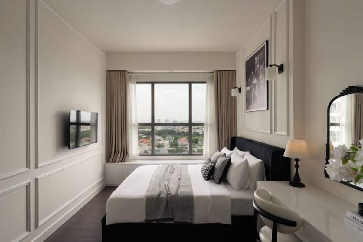 Une chambre d’hôtel avec une grande fenêtre, un lit, une table de chevet, un miroir et un téléviseur.