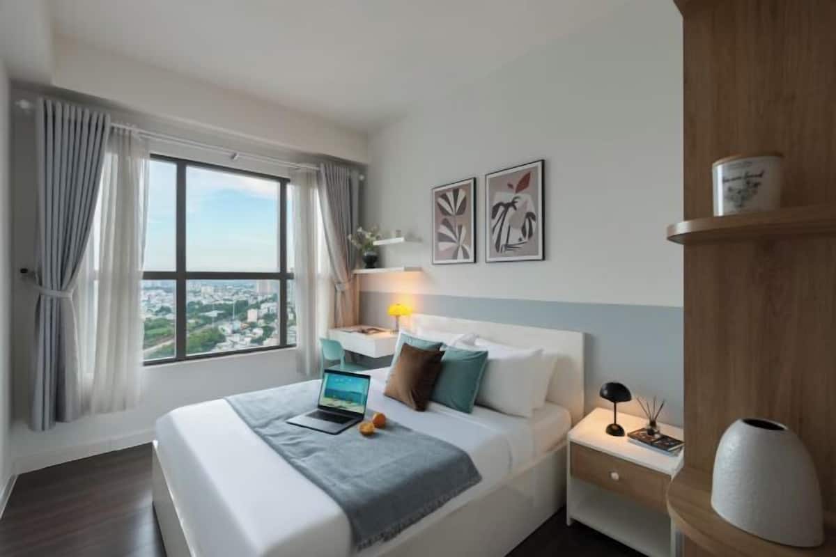 Une chambre d’hôtel avec un lit, un bureau, une lampe, un vase et des œuvres d’art accrochées au mur.