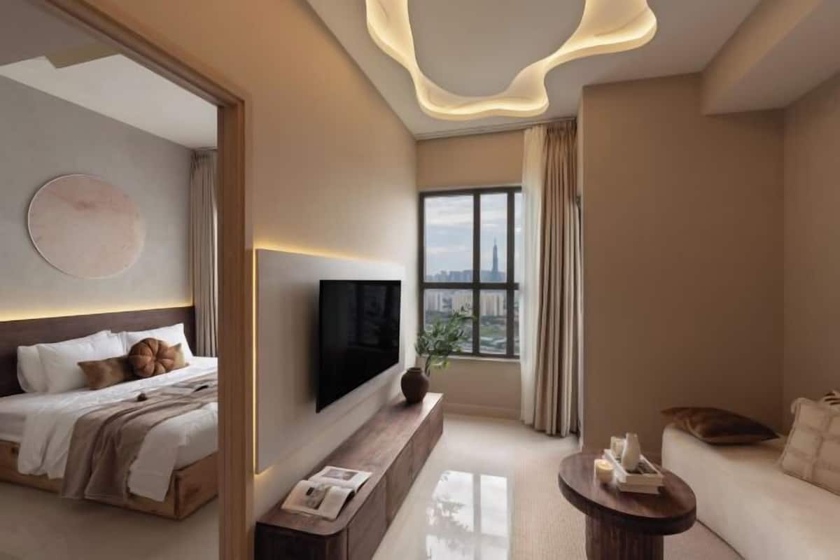 Une chambre d’hôtel moderne équipée d’un lit, d’un téléviseur à écran plat, d’un canapé, d’une table basse et d’une grande fenêtre donnant sur la ville.