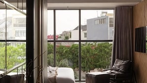 Una sala de estar moderna con un ventanal grande, un sofá, una silla y un televisor montado en la pared.