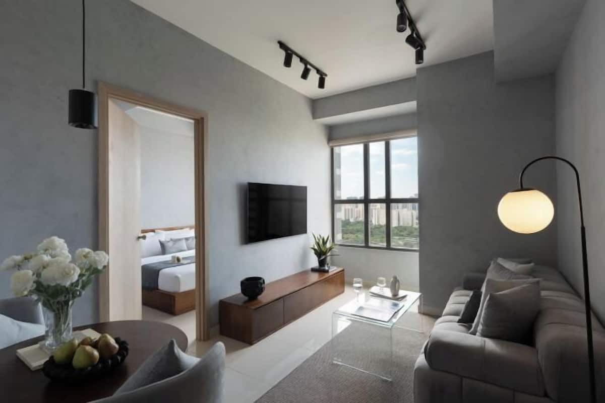 Une chambre d’hôtel moderne dotée d’une télévision à écran plat, d’un canapé, d’une table à manger agrémentée d’un vase de fleurs et d’une grande fenêtre offrant une vue sur la ville.