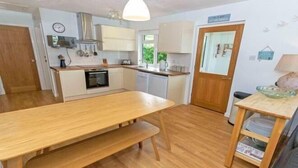 Una cocina compacta con una mesa de madera, un banco y un pequeño comedor.