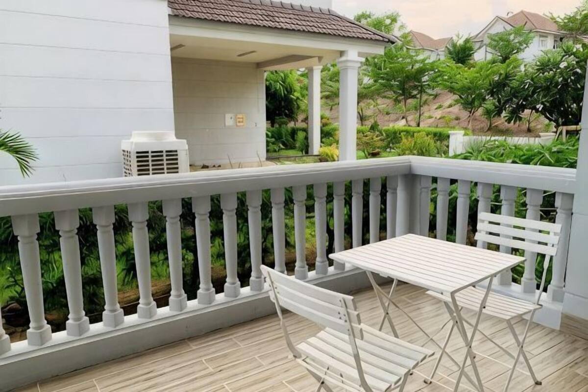 A balcony with a white railing, a table, and two chairs.