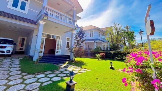 A two-story house with a covered porch, a stone pathway, and a well-maintained lawn. - 4 bedroom Seafront Soan Villa - Sealinks Mui Ne (Phan Thiet)
