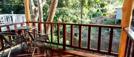 A covered outdoor area with a wooden deck, metal chairs, and a table.