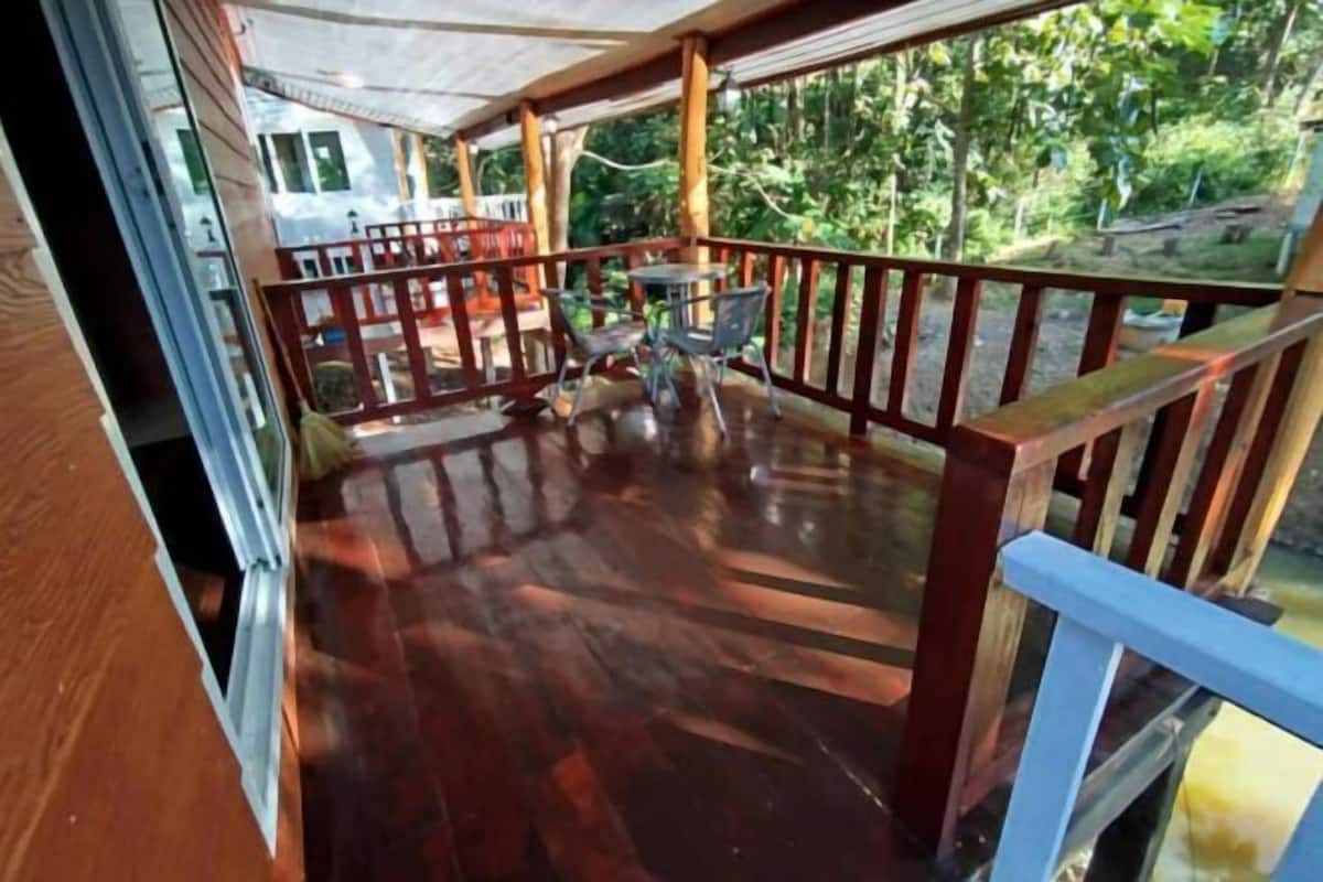 Een houten terras met een balustrade, een tafel en stoelen.