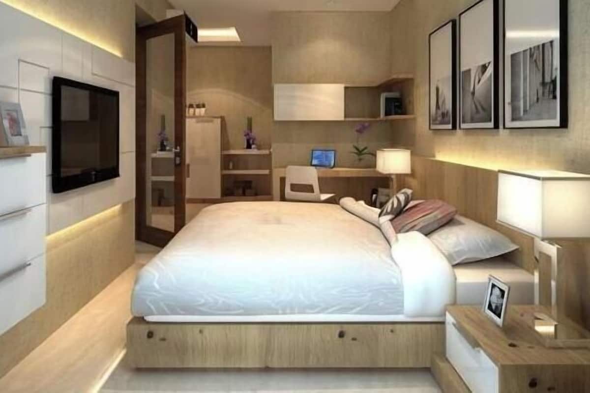 Ein modernes Schlafzimmer mit Bett, Nachttischen, Schreibtisch, Stuhl, Fernseher und gerahmten Bildern an der Wand.