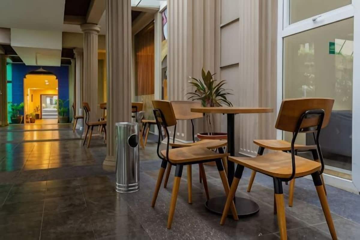 Eine Hotelhalle mit Sitzbereich in der Mitte, einem Papierkorb und einer Zimmerpflanze.