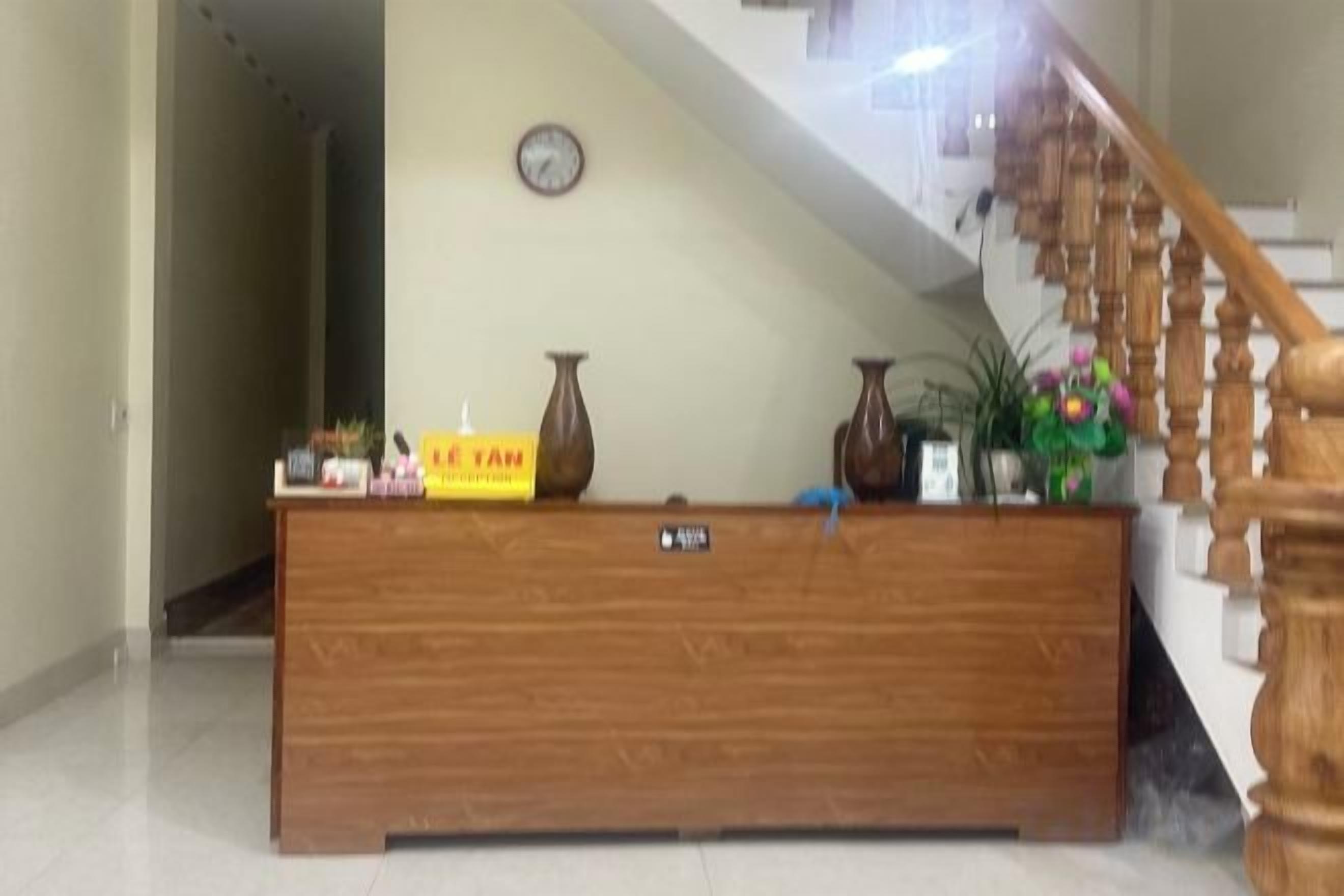 A reception desk with a clock, a sign, and a vase.